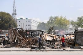 People walk past destroyed vehicles set on fire by gangs in Port-au-Prince, Haiti, on March 25 [File: Ralph Tedy Erol/Reuters]