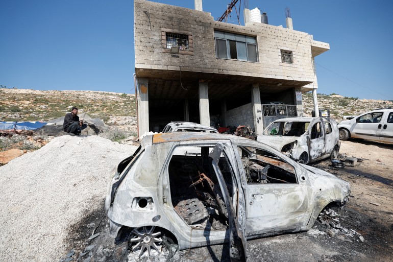 Ein Palästinenser sitzt in der Nähe eines beschädigten Hauses und beschädigter Autos, nachdem israelische Siedler am 13. April 2024 das Dorf al-Mughayyer im von Israel besetzten Westjordanland angegriffen haben