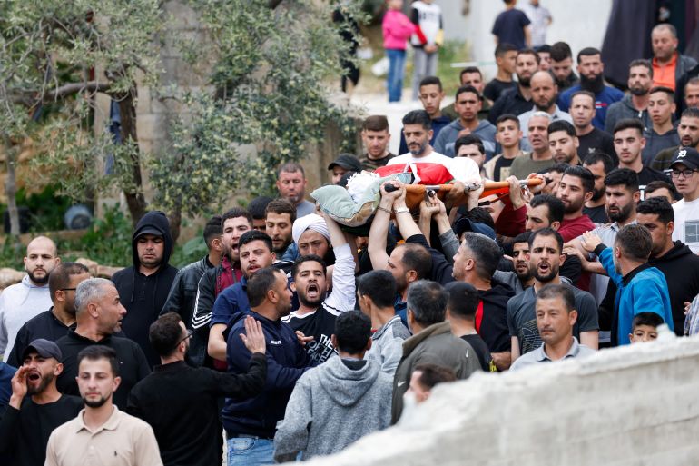 SENSITIVE MATERIAL. THIS IMAGE MAY OFFEND OR DISTURB Mourners carry the body of a Palestinian who was killed during an attack by Israeli settlers on the village of al-Mughayyer, in the Israeli-occupied West Bank, April 13, 2024. REUTERS/Mohammed Torokman