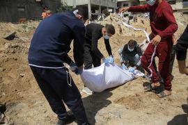 Palestinians cover a body that was buried in a mass grave in the northern Gaza Strip [Mahmoud Issa/Reuters]
