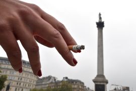 A woman smokes in Trafalgar Square in central London [File: Toby Melville/Reuters]