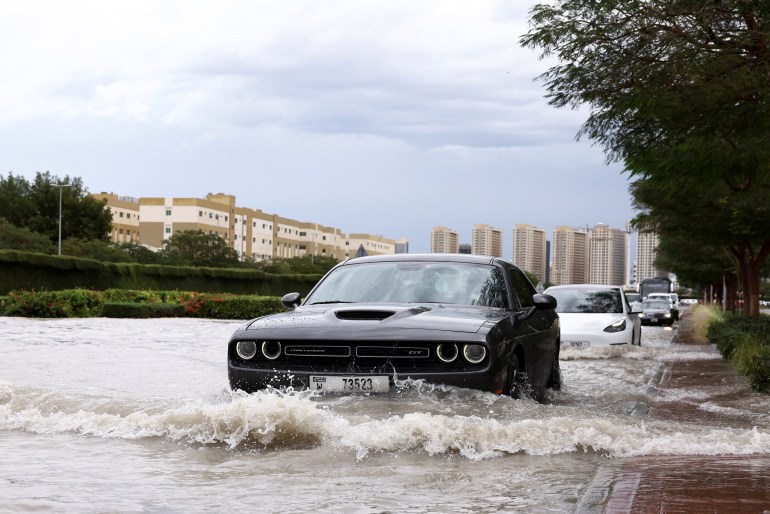 پس از باران‌های شدید در دبی، خودروها از میان آب در خیابان‌های سیل‌زده می‌روند.