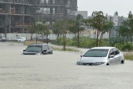 Cars attempt to navigate a flooded street in Dubai. [Abdel Hadi Ramahi/Reuters]
