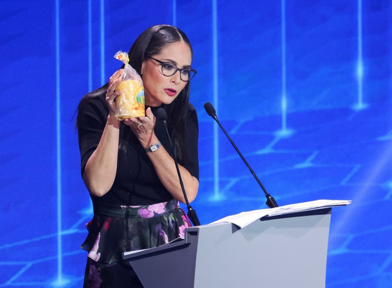 Zulay Rodriguez holds up a bag of tortillas from a debate-stage podium.
