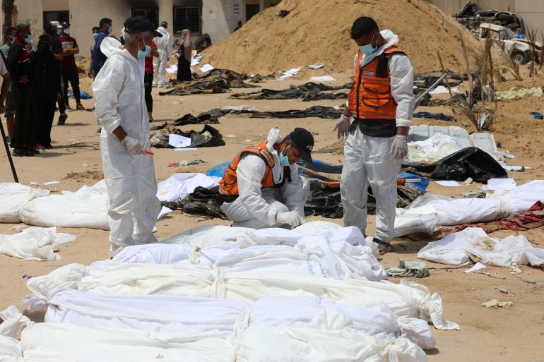 People work to move into a cemetery bodies of Palestinians killed during Israel's military offensive and buried at Nasser hospital, amid the ongoing conflict between Israel and the Palestinian Islamist group Hamas, in Khan Younis