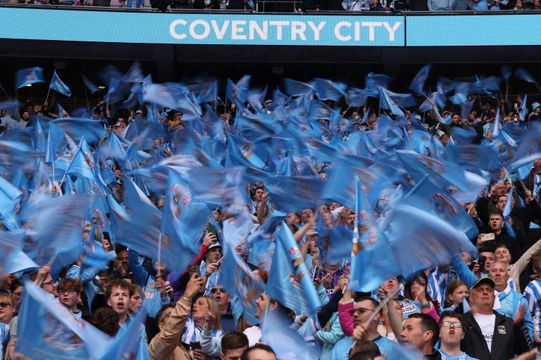 Coventry City fans with blue flags inside the stadium 