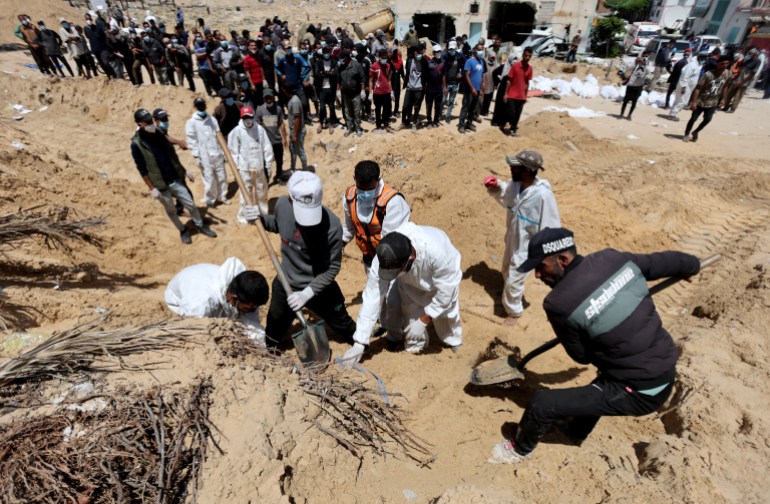 Pessoas trabalham para transportar para um cemitério corpos de palestinos mortos durante a ofensiva militar de Israel e enterrados no hospital Nasser