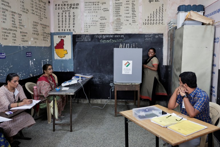 Eine Frau lächelt, während sie mit dem Wahlbeamten spricht, während sie in einem Wahllokal während der zweiten Phase der Parlamentswahlen in Bengaluru, Karnataka, Indien, am 26. April 2024 abstimmt