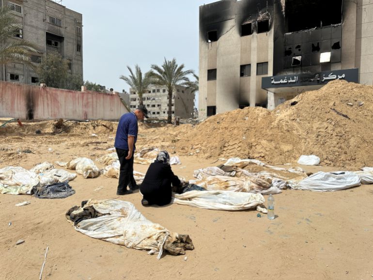 People work to recover the bodies of Palestinians killed during Israel's military offensive and buried at Nasser hospital,