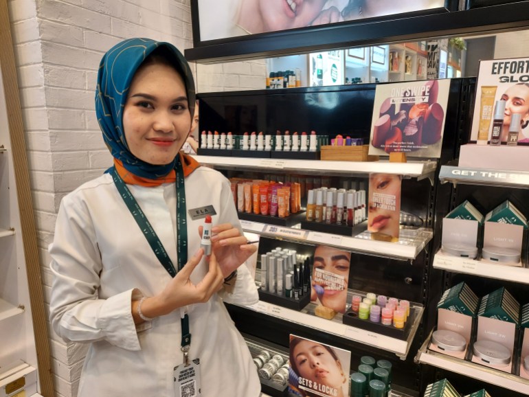Die Verkäuferin von Body Shop, Ela, plant für die Feiertage einen extravaganten Make-up-Look, einschließlich Lippenstift in leuchtenden Farben [Aisyah Llewellyn/Al Jazeera]