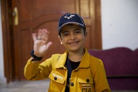 Aslan, a nattily dressed, smiley little boy in his home in Idlib, Syria [Ali Haj Suleiman/Al Jazeera]