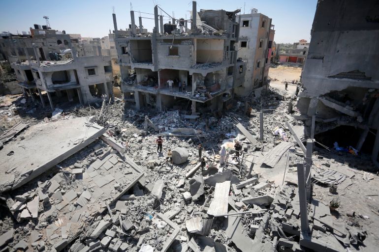 Palestinians living in al-Maghazi Refugee Camp collect the usable items among the rubble of the destroyed buildings following an Israeli attack in Deir al-Balah, Gaza