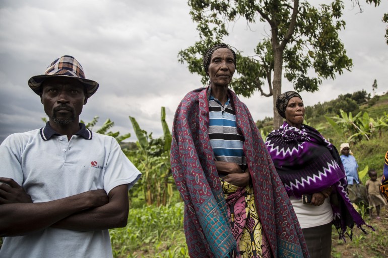 Josepha Mukaruzima, 70 (C), a Tutsi woman from Ruseke village, whose entire family was killed, stands with Jean-Claude Mutarindwa, 42 (L), a Hutu from neighbouring Giheta village, at the border between Musambira and Nyarubaka sectors of Kamonyi District on March 4, 2019. In the 1994 genocide in Rwanda, majority Hutu's from Giheta turned on their long-time neighbours in Ruseke. Mutarindwa was a young man from the village of Giheta. Unlike his brothers, he did not pick up a machete to kill, and that helped him be one of the first to lay the foundation stones for reconciliation. The neighbours are now re-learning to share all they have, including a well-spring at the bottom of the valley. More than a thousand residents of the town were massacred in the days following the outbreak of inter-ethnic violence, a genocide in which over 800,000 mostly Tutsi people were slaughtered between April to July 1994, according to the UN. [Jacques Nkinzingabo/AFP]