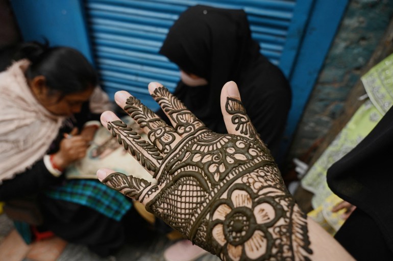A girl shows her hand decorated with henna at a market area ahead of Eid al-Fitr, which marks the end of the Muslim holy festival of Ramadan, in Srinagar, on April 20, 2023 [Tauseef Mustafa / AFP]
