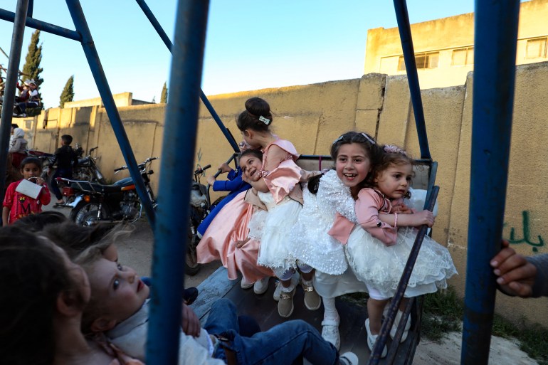 Am ersten Tag von Eid al-Fitr, dem Ende des muslimischen Fastenmonats Ramadan, reiten Kinder am 21. April 2023 in der von Rebellen kontrollierten Stadt Maaret Misrin in der nordwestlichen Provinz Idlib in Syrien auf einer Schaukel [Abdulaziz Ketaz / AFP]