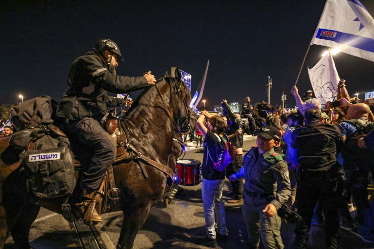 Полицейский верхом на лошади пытается разогнать протестующих. Сейчас ночь