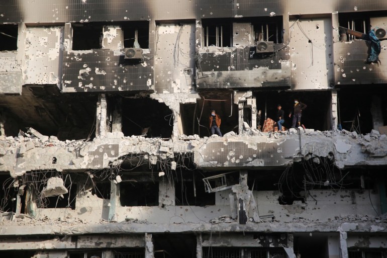 Palestinians gather around the burned and destroyed Al-Shifa Hospital