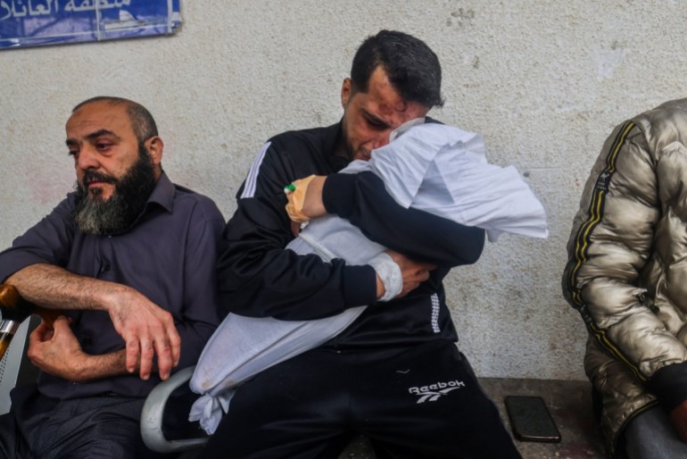 Palestinian father Ashraf cries as he holds the body of one of his two daughters
