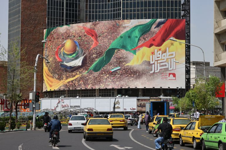 Iranians drive past a pro-Palestinian billboard in central Tehran on April 13