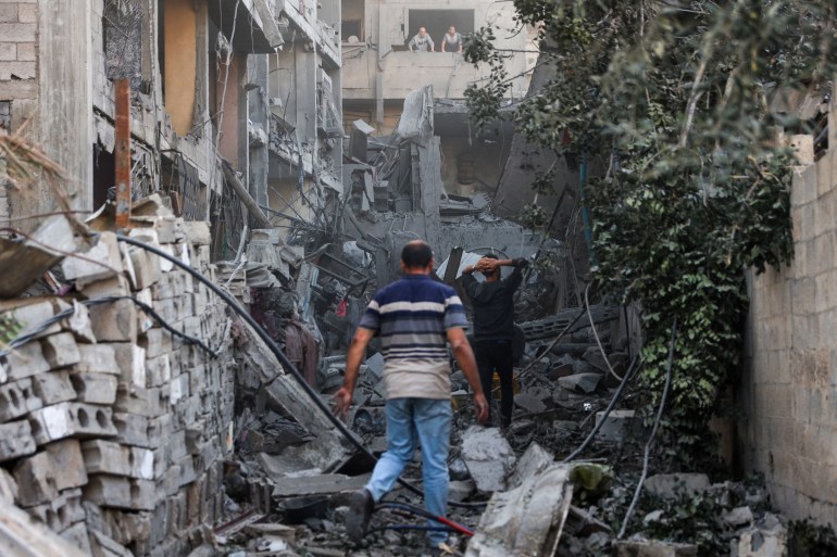 فلسطینی ها پس از بمباران اسرائیل در محله الدراج، آوارهای یک ساختمان را بازرسی می کنند