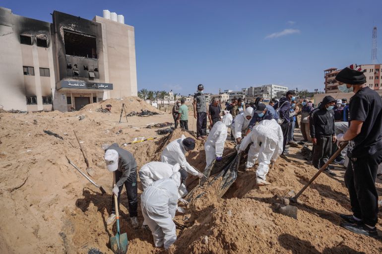 Palestinian health workers unearth a body buried by Israeli forces in Nasser hospital compound in Khan Yunis in the southern Gaza Strip on April 21