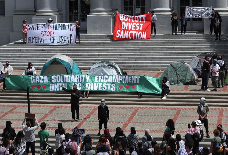 students hold a banner that says UC Berkley divest