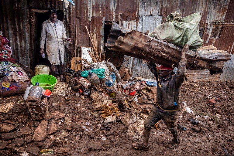 A man gathers some of his belongings as other carries several materials after their houses were destroyed by floods following torrential rains at the Mathare informal settlement in Nairobi, on April 25, 2024. - Torrential rains triggered floods and caused chaos across Kenya, blocking roads and bridges and engulfing homes in slum districts. The death toll from flash floods in Kenya's capital Nairobi has risen to 13 on April 25, 2024, police said. Kenyans have been warned to stay on alert, with the forecast for more heavy rains across the country in the coming days. 
