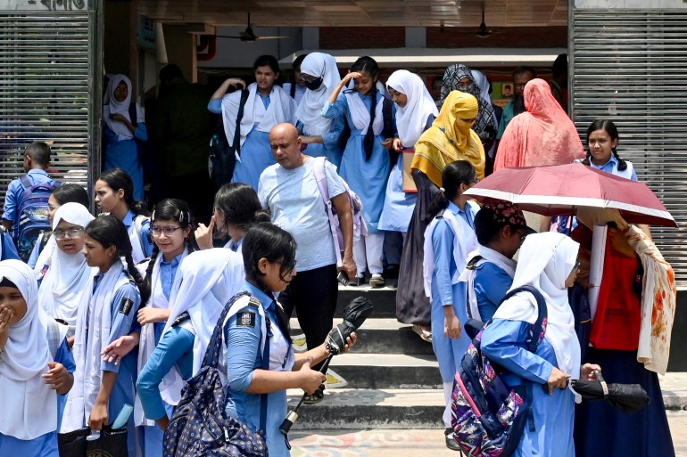 An einem heißen Sommertag in Dhaka am 28. April 2024, inmitten der anhaltenden Hitzewelle, verlassen Schüler ihr Schulgelände mit Regenschirmen.  – Millionen von Schülern kehrten am 28. April in ihre wiedereröffneten Schulen in ganz Bangladesch zurück
