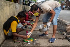 A man distributes food to homeless people on a pavement during a nationwide lockdown to curb the spread of new coronavirus in Gauhati, India, Sunday, April 19, 2020. (AP Photo/Anupam Nath)