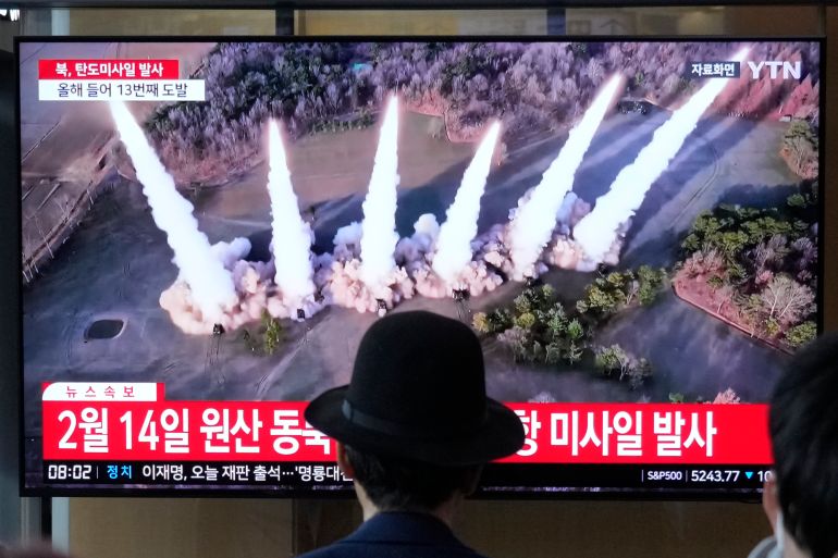 A person in a hat watching a news bulletin about North Korea's missile launch The screen is showing file footage from a previous test.