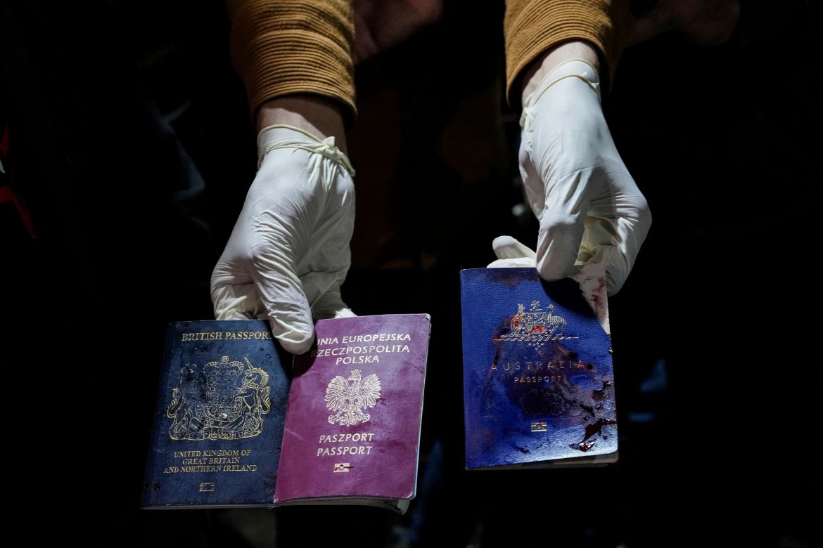 A man displays blood-stained British, Polish, and Australian passports