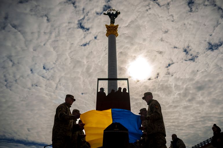 Militares ucranianos colocam a bandeira nacional no caixão de seu colega caído Vadym Popelniuk, nascido em 1991, durante um serviço religioso na Praça da Independência em Kiev, Ucrânia, sexta-feira, 5 de abril de 2024. (AP Photo/Vadim Ghirda)