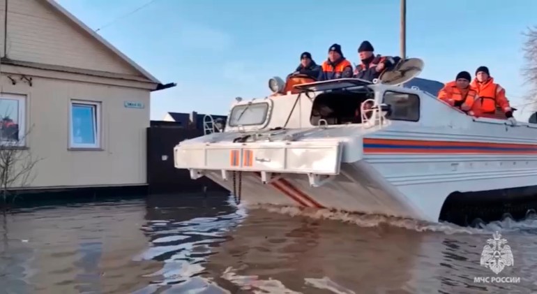 In this grab taken from a video released by the Russian Emergency Ministry Press Service on Saturday, April 6, 2024, emergency workers aboard an amphibious vehicle look to evacuate local residents after a part of a dam burst causing flooding, in Orsk, Russia.