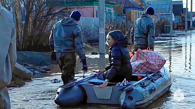 In this image taken from a video released by the Russian Emergency Ministry Press Service on Saturday, April 6, 2024, emergency workers pull a boat as they evacuate a local resident after a part of a dam burst causing flooding, in Orsk, Russia.