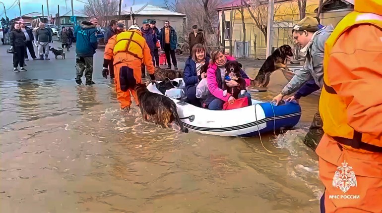 In this image taken from a video released by the Russian Emergency Ministry Press Service on Saturday, April 6, 2024, emergency workers evacuate local residents with their pets after a part of a dam burst causing flooding, in Orsk, Russia. Floods hit a city in the Ural Mountains areas after a river dam burst there, prompting evacuations of hundreds of people, local authorities said. The dam breach in Orsk, a city less than 20 kilometers north of Russia's border with Kazakhstan, occurred on Friday night, according to Orsk mayor Vasily Kozupitsa.