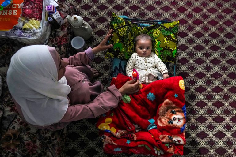 Rola Saqer sits beside her baby Masa Mohammad Zaqout in Zawaida, central Gaza, April 4, 2024. Zaqout was born Oct. 7, the day the Israel-Hamas war erupted.