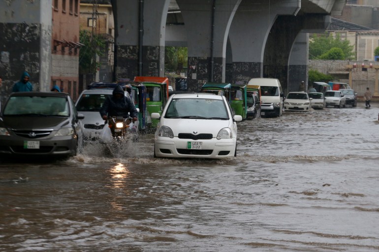 A motorcyclist and car drivers drive through a flooded road caused by heavy rain in Peshawar, Pakistan, Monday, April 15, 2024. Lightening and heavy rains killed dozens of people, mostly farmers, across Pakistan in the past three days, officials said Monday, as authorities declared a state of emergency in the country's southwest following an overnight rainfall to avoid any further casualties and damages. (