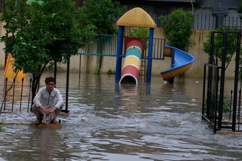 A man sits in a flooded park caused by heavy rain in Peshawar, Pakistan, on April 15