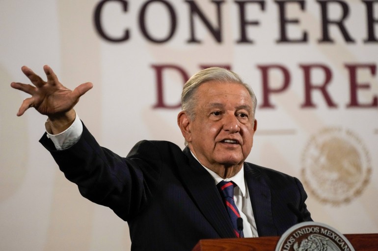 Andres Manuel Lopez Obrador spreekt op een podium en steekt een uitgestrekte hand op als gebaar.