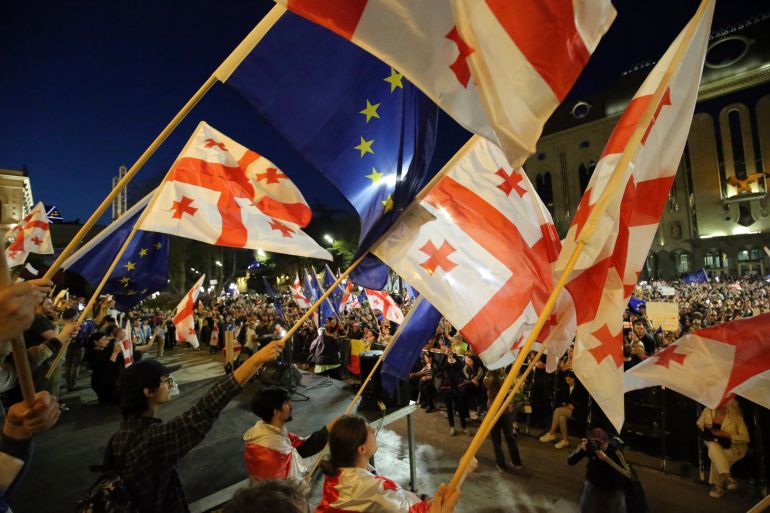 Protesters waving Georgian flags at a protests in Tbilisi. Some are waving EU flags.