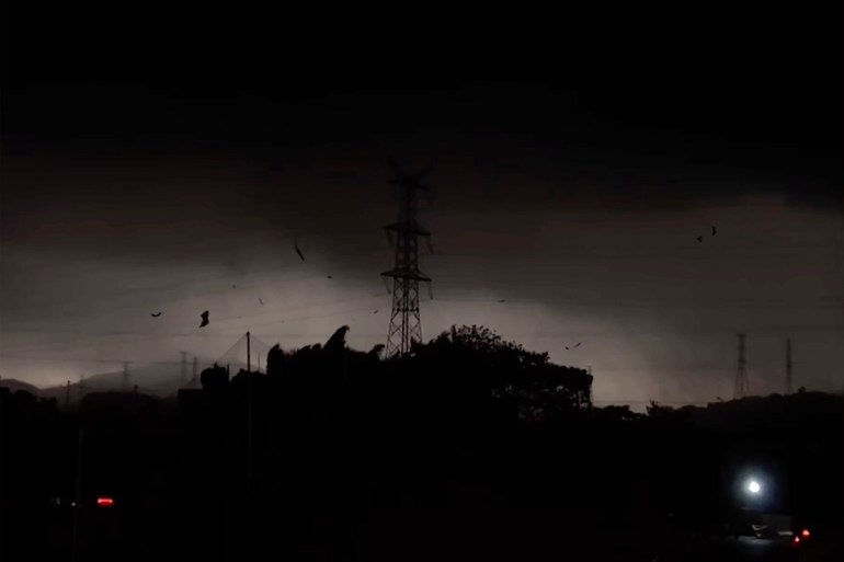 The tempest  implicit    the Baiyun district. The entity  is astir   achromatic  and an energy  pylon is silhouetted against the lighter clouds.. There is debris being blown astir  by the wind.