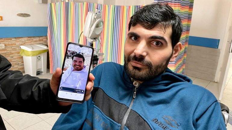 Fadi'nin elinde kardeşinin resminin bulunduğu bir telefon var