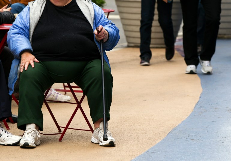 An overweight woman sits on a chair in Times Square in New York, US