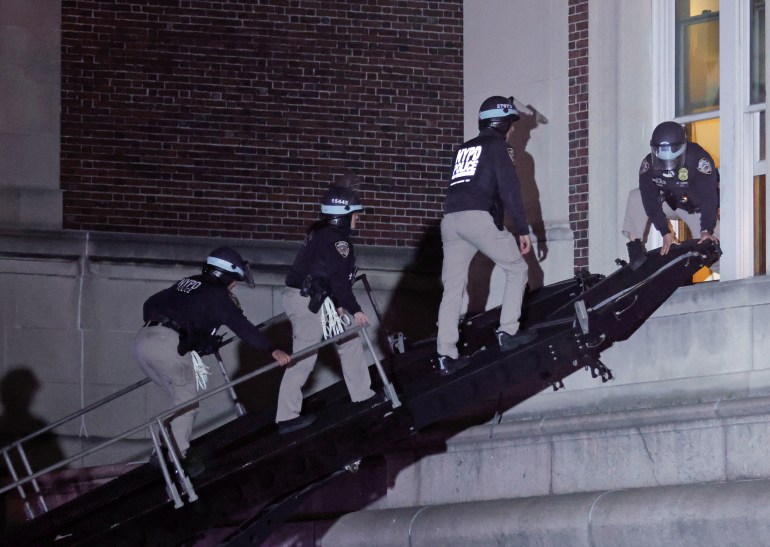 Police walking along a ladder extended from the top of a truck to get into a window on the Columbia university campus