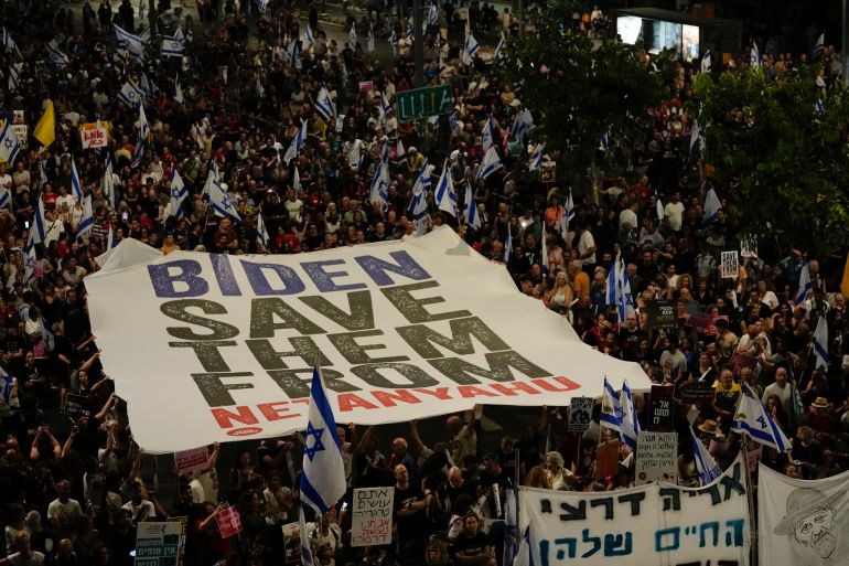 people hold a large banner saying Biden save them from Netanyahu
