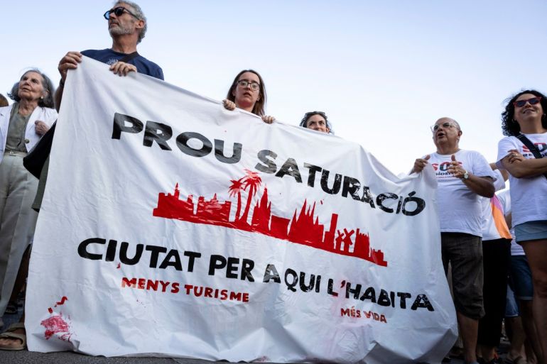 Protesters hold a banner which reads as Enough saturation, the city for those who live in it, as they take part in a demonstration to protest against overtourism and housing prices on the island of Mallorca