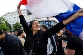 A woman waves the French flag as she reacts to projected results after the second round of the legislative elections, Sunday, July 7, 2024 in Nantes, western France.