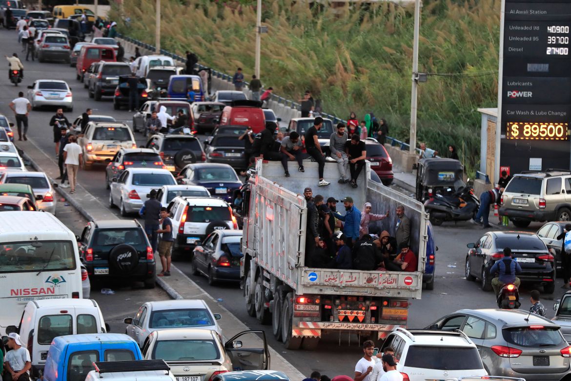 Lebanese citizens who fled on the southern villages amid ongoing Israeli airstrikes Monday, sit on their cars at a highway that links to Beirut city