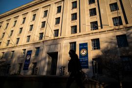 A woman walks past the US Department of Justice Building, in Washington, U.S., in December 2020. On Tuesday, the department charges two Chinese nationals with spying and trying to recruit US military assets. [Al Drago/Reuters]