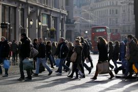 People walk across Oxford Circus in London, United Kingdom, where work-related immigration has fallen due to tighter visa requirements [File: Sang Tan/AP]